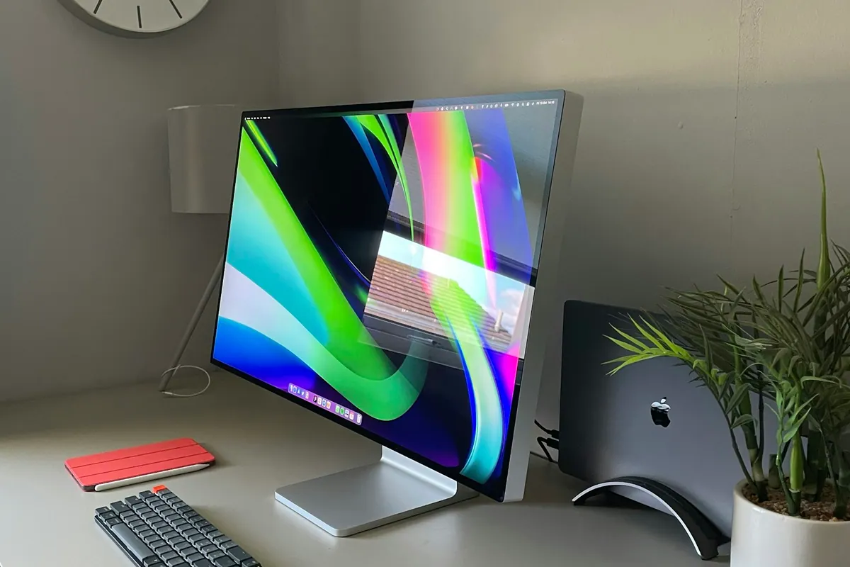 A minimal home workspace with a laptop and display on a white desk