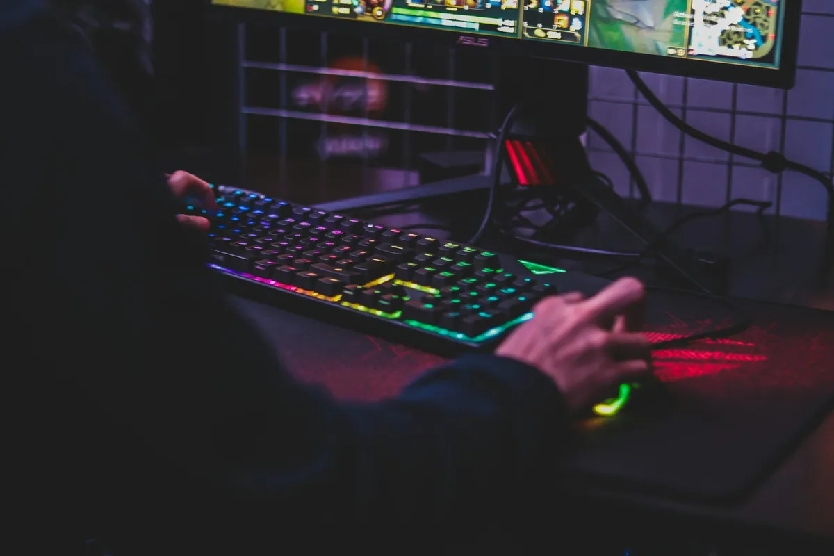 Hands using a gaming keyboard and mouse at a desktop computer