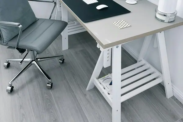 Bright home office with a white desk, computer, plants and a gray chair