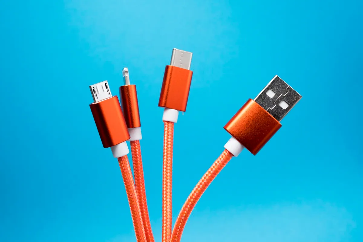 Several orange charging cables with different connectors against blue