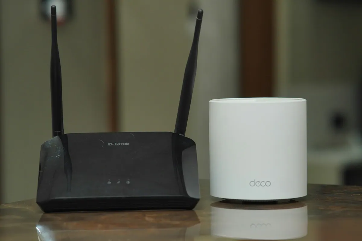 A traditional router and a mesh networking unit on a table